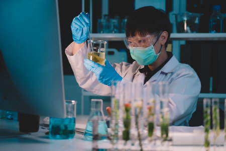 scientist dripping substances of ecological skin care beauty products in night lab development concept Research with plants and scientific extraction in glassware. Green alternative herbal medicine for physical health careの写真素材