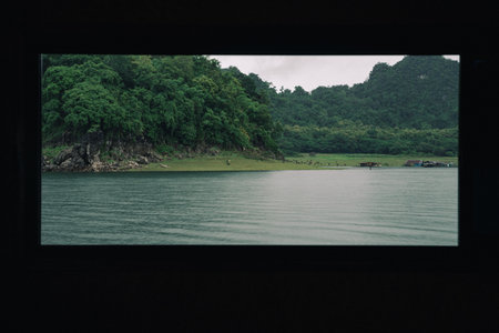 The mountain scenery, with its blue sky and fluffy clouds, frames a tranquil lake and dam, while a...