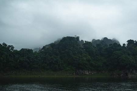 The mountain scenery, with its blue sky and fluffy clouds, frames a tranquil lake and dam, while a...