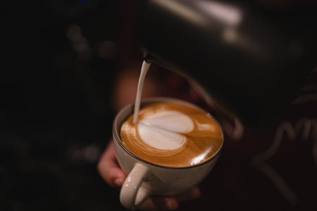 In bustling cafes, the barista crafted a hot drink, blending rich espresso and steamed milk into a latte adorned with intricate art, making each sip a delightful experience.の写真素材