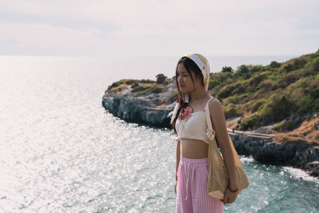 The woman enjoyed a solo travel vacation, basking in the summer sun on the beach, surrounded by nature, and embracing the freedom of a peaceful holiday getaway.の写真素材