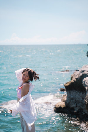 The woman enjoyed a solo travel vacation, basking in the summer sun on the beach, surrounded by nature, and embracing the freedom of a peaceful holiday getaway.の写真素材