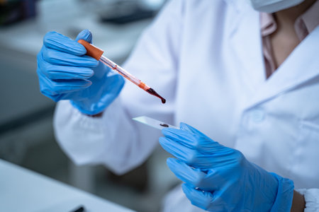 In the laboratory, blood is carefully dripped into test tubes for medical and biology research, with scientists conducting tests to advance medicine and scientific knowledge.の写真素材