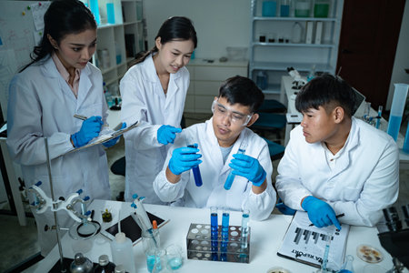 In the laboratory, a group of professional researchers gather around a chemical tube, checking samples for medical analysis and conducting chemistry experiments to ensure accurate results.の写真素材
