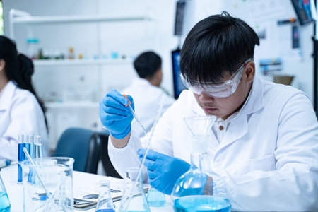 In the laboratory, researchers carefully drip substances into a tube during an experiment, applying...