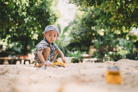 Children play happily in the summer garden, digging in the sand with toys, each person lost in the joy of childhood memories and carefree laughter under the sun.の写真素材