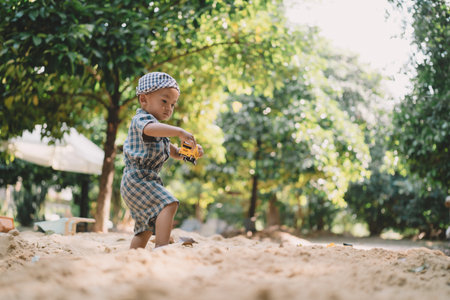 In the summer garden, a boy joins other children playing with toys in the sand, each person reliving the simple joys of childhood under the warm, golden sun.の写真素材