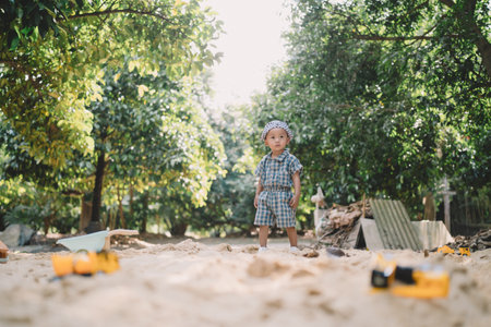 In the summer garden, a boy joins other children playing with toys in the sand, each person reliving the simple joys of childhood under the warm, golden sun.の写真素材