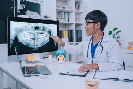 At the clinic, the dentist used an x-ray to examine the patientâ€™s teeth, discussing treatment...