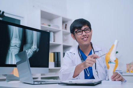 The doctor in the clinic used a detailed model of knee anatomy during the patient's check-up exam,...