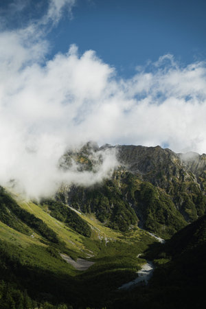 Travel to the high mountain peak where fog and mist drift across the landscape, painting the sky with silver light and turning the quiet scenery into radiant sunrise sky.の写真素材