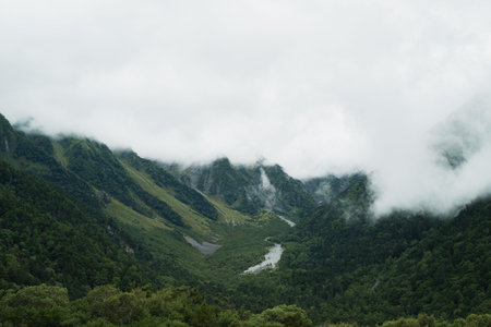Travel to the high mountain peak where fog and mist drift across the landscape, painting the sky with silver light and turning the quiet scenery into radiant sunrise sky.の写真素材