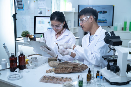 A young scientist in a laboratory examining aquatic plants through a magnifying glass focusing on...