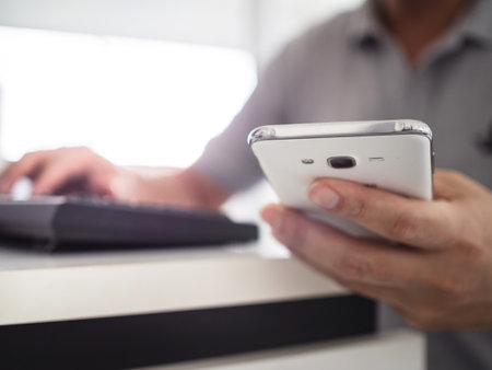 Man hands holding and working with mobile phone and computerの写真素材
