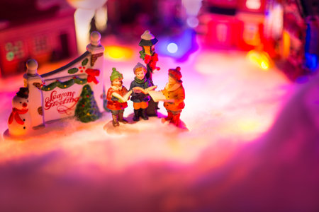 kid choir singing next to holiday greeting sign with snowy christmas village in the background. seasons greeting festive conceptの写真素材