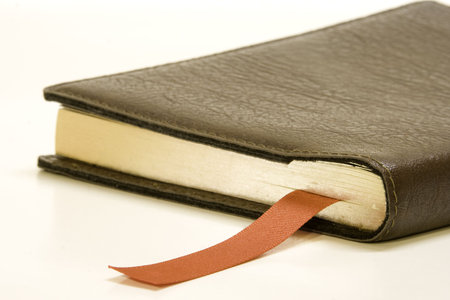 Old book with ribbon bookmark against white background.の写真素材