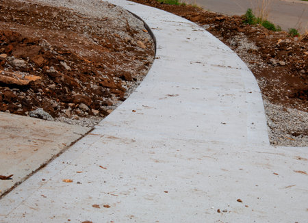 new construction of a sidewalk showing piles of dirt and corner of drivewayの写真素材