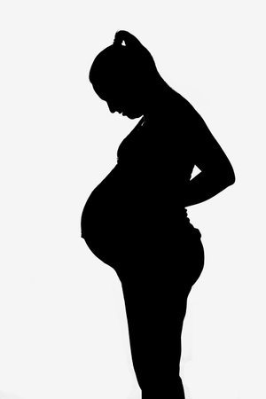 Silhouette of a pregnant woman looking down. の写真素材
