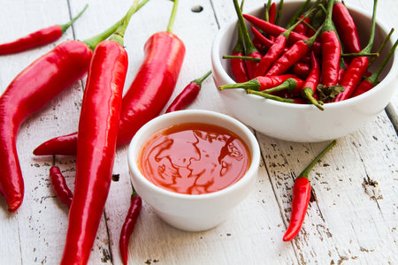 Peppers and chili sauce on white wooden floor.のeditorial素材