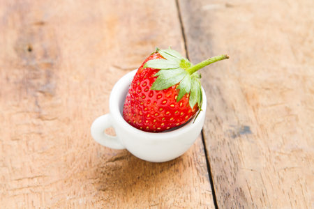 Strawberry in a glass placed on a wooden table.の写真素材