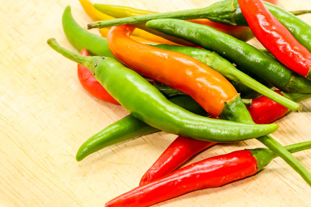 Closeup of red,orange and green chili pepper on wooden background