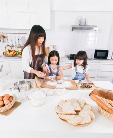 Family cooking time : Happy mother and two dauther help cooking bake together in kitchen at homeの写真素材