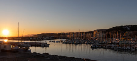 Beautiful sunset panoramic view of a port at sunset with multiple sailboats. Arenys de Mar village in El Maresme coast, Barcelona.の写真素材