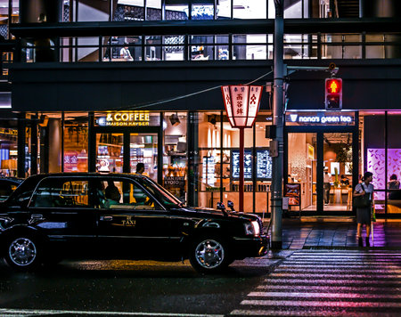 Classic japanese Toyota taxi in front of a pedestrian crosswalk and a few shops. Night photography.のeditorial素材