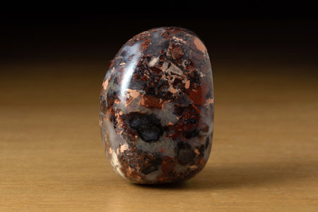 Polished Sard Jasper gemstone from Brazil over a wooden table