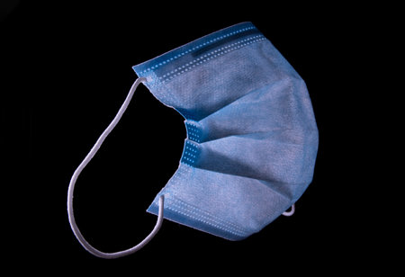Simple blue standard surgical mask isolated on blackの写真素材