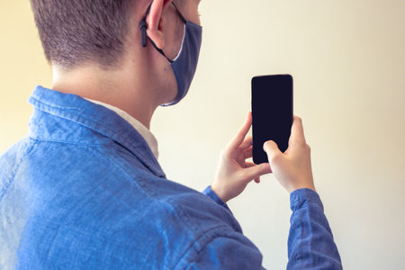 Business elegant man using a phone / mobile for taking a photo with a face mask on.の写真素材