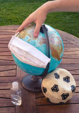 Hand holding a mask on a earth globe represents the global pandemicの写真素材