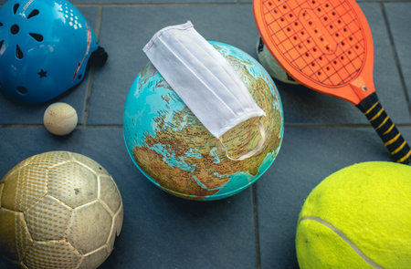 football, tennis and baseball balls with an world in the middle and a maskの写真素材