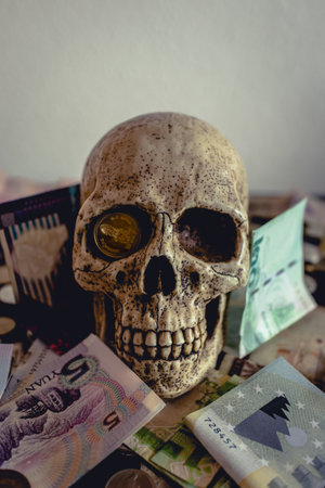Skull with different coins on a black table. Pirates style. Can represent economical crisis, death etcの写真素材