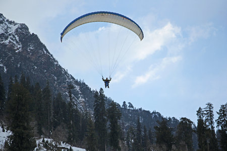 Manali, India - December 26, 2013: Paragliders flying in tandem in the Himalayas during winter season in Solang Valley in Manali, India.のeditorial素材