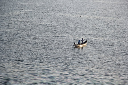 Panjim, Goa, India - January 23, 2017: Unidentified fishermen in boat retrieve the trap net laid the previous night for catching fish in the Mondovi River in Panjim, Goa, Indiaのeditorial素材
