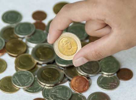 Hand catches a coin with coins in backgroundの写真素材