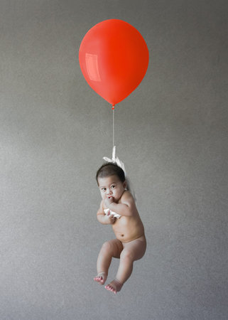 Baby float with a red balloonの写真素材