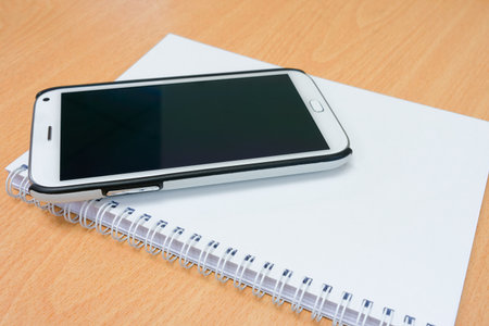 Conceptual image of smart phone and notebook on wooden tableの写真素材