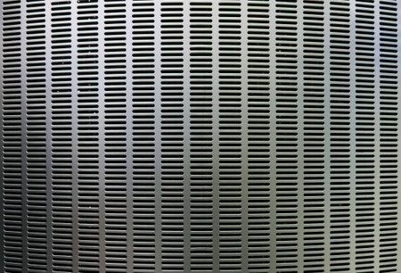 Silver curved metal background with elongated grill slots and light reflectionの写真素材