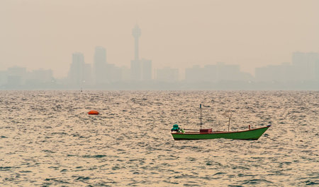 A fishing boat with Pattaya city in background in the eveningの写真素材