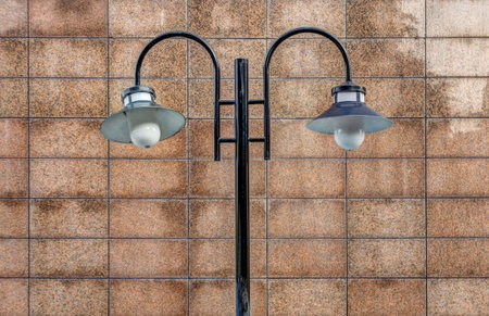 A vintage lamppost is a light on a post on a walkway at the edge of a streetの写真素材