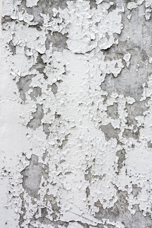 Cracking and peeling paint on a white concrete wallの写真素材