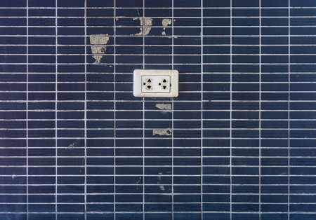 Old electric plug outlet on ceramic tiles wall