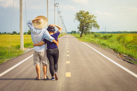 Romantic young Asian couple embracing on countryside road. They are tourist and traveling in Thailand, Southeast Asia.の写真素材