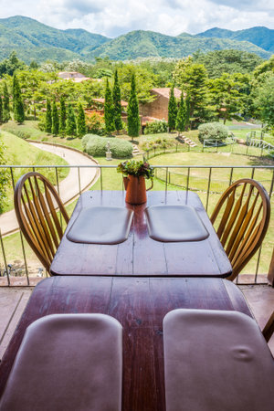 Vintage vase, wooden table and chair on terrace with mountain view. The decoration of a restaurant.の写真素材