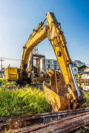Old backhoe and steel rods at construction site. Backhoe is also called a rear actor or back actor.