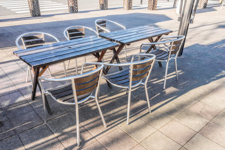 Modern wooden tables and chairs with metal frame of restaurant. They are on sidewalk.の写真素材