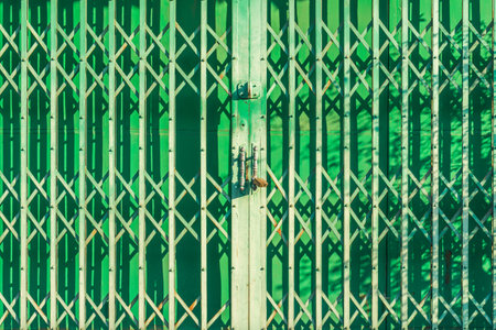 Vintage folding green metal gate with door lock. It is a door of traditional building shop in Thailand.の写真素材