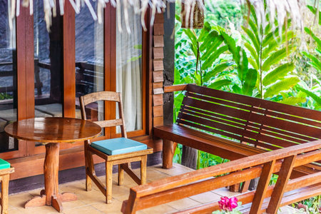 Vintage wooden chairs, benches and table on a home porch. They are traditional furnitures in Thailand, Asia.の写真素材